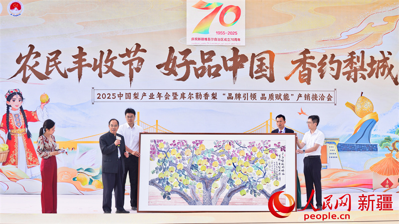 双方签署战略合作协议后，山东莱阳梨产业协会向新疆巴州库尔勒香梨协会赠送画作。人民网 李欣洋摄